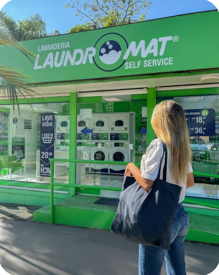 Cliente com uma bolsa de roupas em frente a uma lavanderia Laundromat