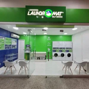 Fachada envidraçada de uma unidade Laundromat, com cadeiras e máquinas ao fundo